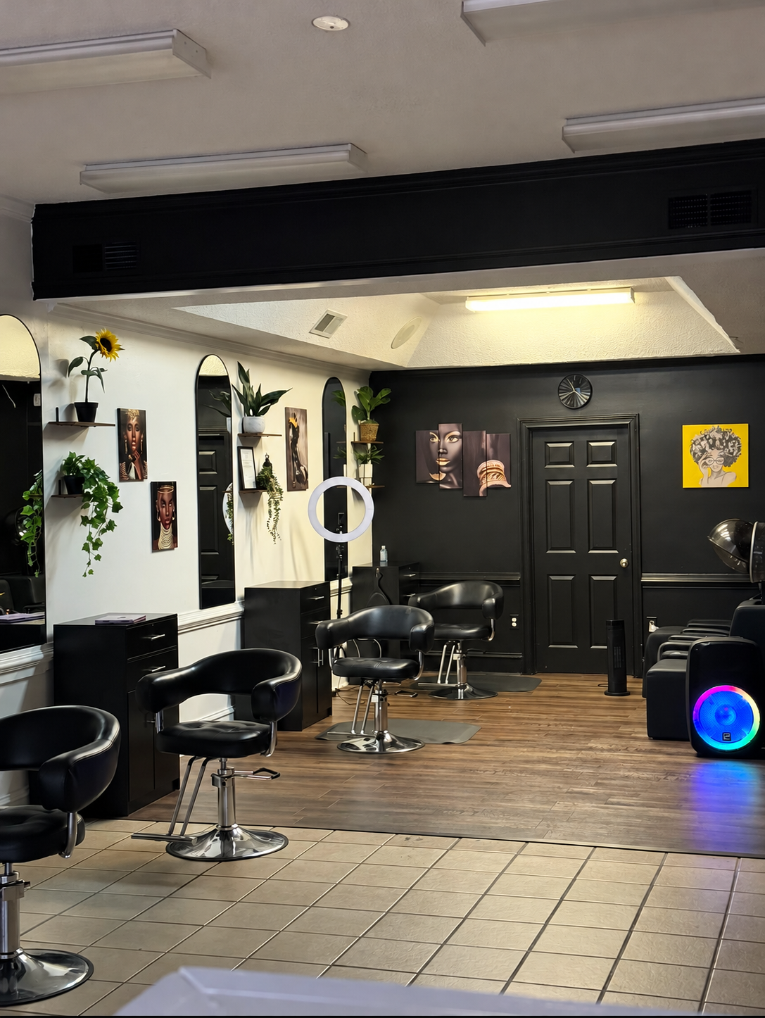 Inside Luxury Locs Beauty Spa, with black salon chairs, arched mirrors, plants, and artwork